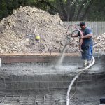 A concrete operator uses a gunite nozzle to spray an in-ground pool in Madisonville, Louisiana.