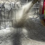 A concrete operator with King Gunite uses a gunite noozle to spray a swimming pool under construction in Metairie, Louisiana.