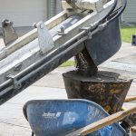 Gunite pours from a volumetric mixer into a nozzle hopper at a swimming pool construction site in Metairie, Louisiana.