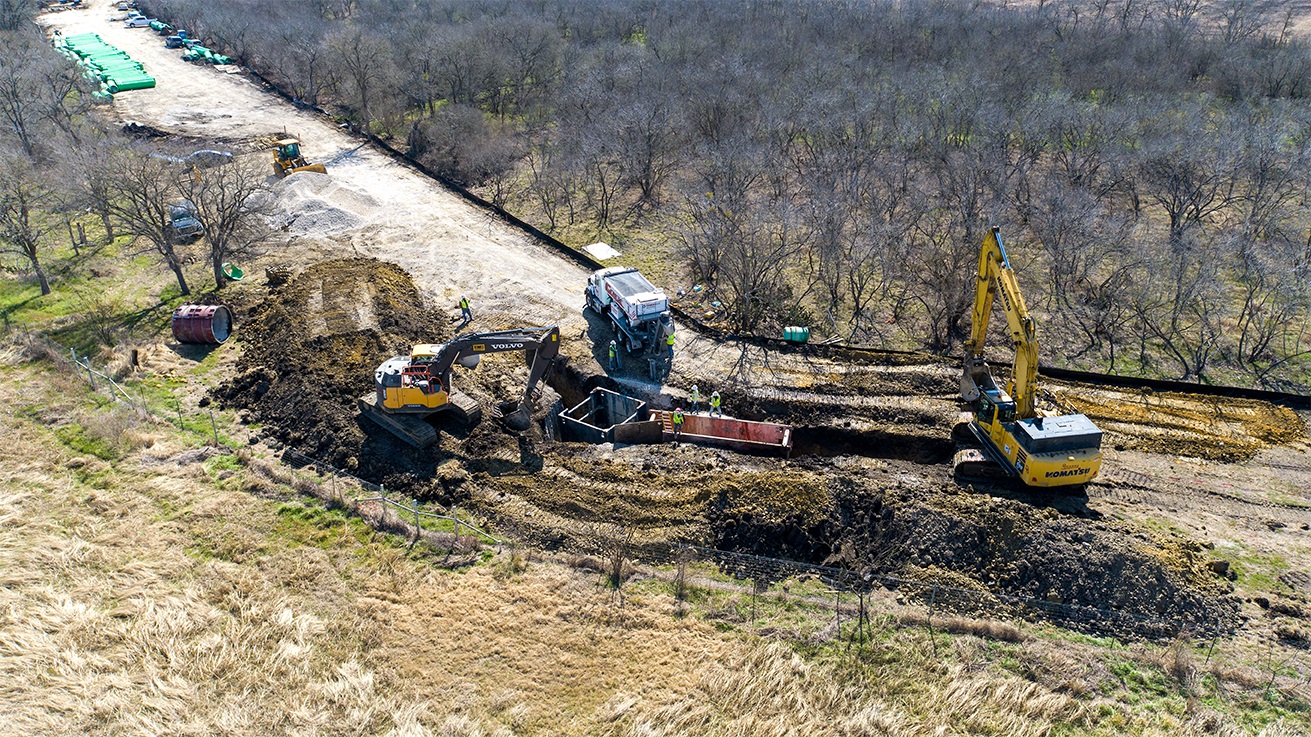Aerial photo of 2 excavators and a volumetric mixer at an underground utility worksite in Texas.